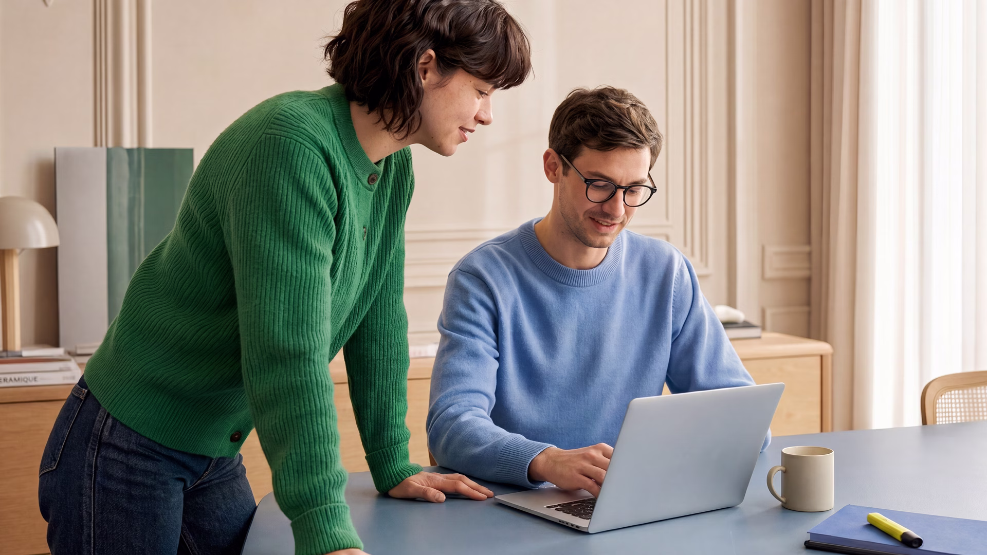 Two colleagues smiling at a laptop in an office after winning a public tender with Tengo