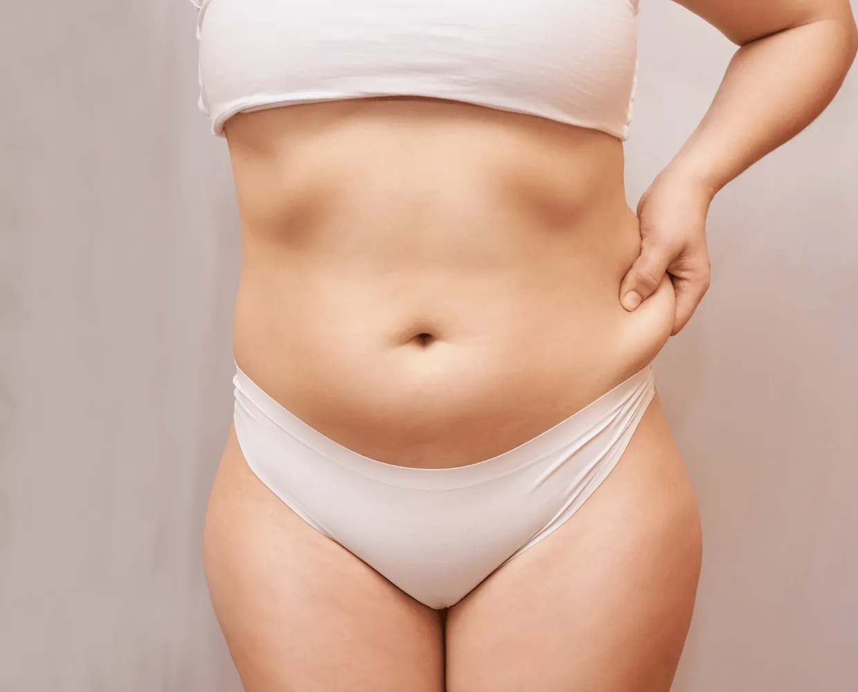 Femme pinçant la peau relâchée de son ventre