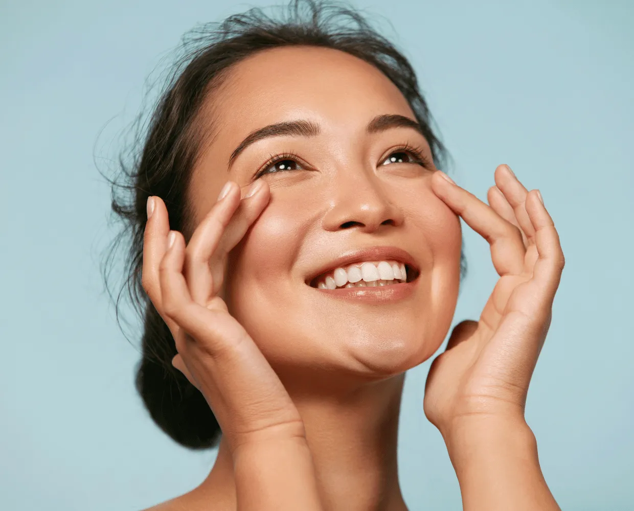 Femme souriante effleurant son visage, peau lumineuse
