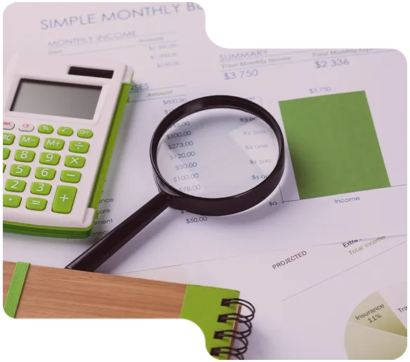 Taschenrechner, Lupe und Notizbuch liegen auf Dokumenten mit Monatsbudget und Diagrammen.
