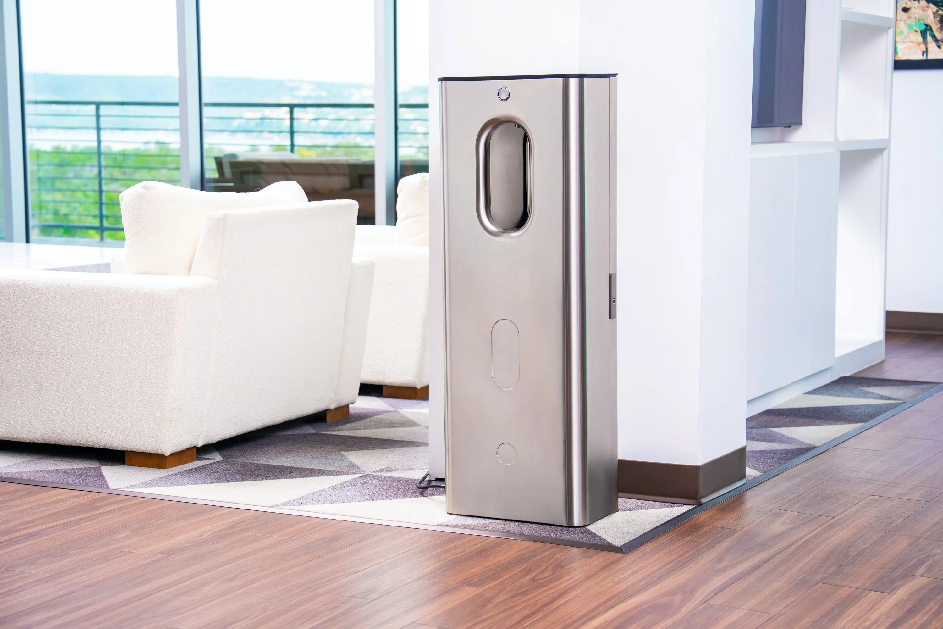 Tall stainless steel Kara Pure air-to-water dispenser in a bright living room with white sofas