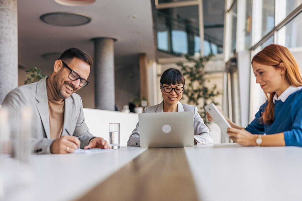 Office setting with three team members smiling and conversing