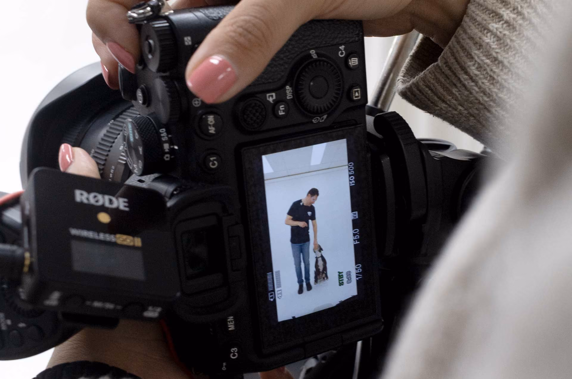 Close-up of a digital camera screen showing a man training a dog in a white room.