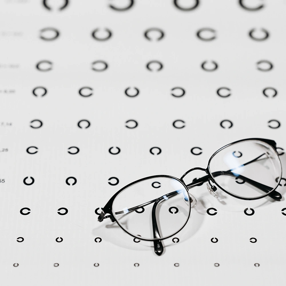 Eine Brille liegt auf einer Sehtafel mit Reihen von schwarzen Landolt-C-Symbolen.