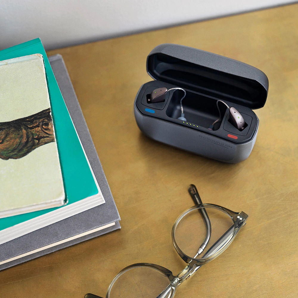 Resound Hinter-dem-Ohr-Hörgeräte Ladestation auf einem Tisch neben einer Brille
