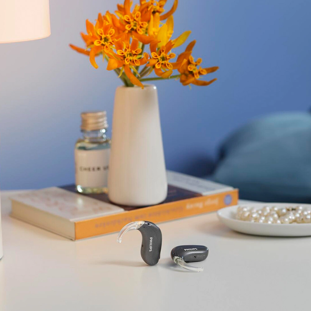 Philips Hinter-dem-Ohr Hörgeräte auf einem Tisch neben einer Blume