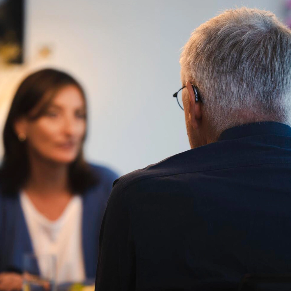 Mann mit Hörgeräte von Philips sitzt an einem Tisch mit einer Frau