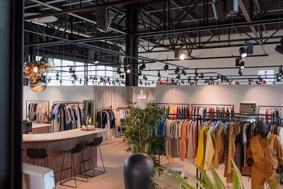 D-LUX office and showroom with clothing racks and a glass-walled meeting space