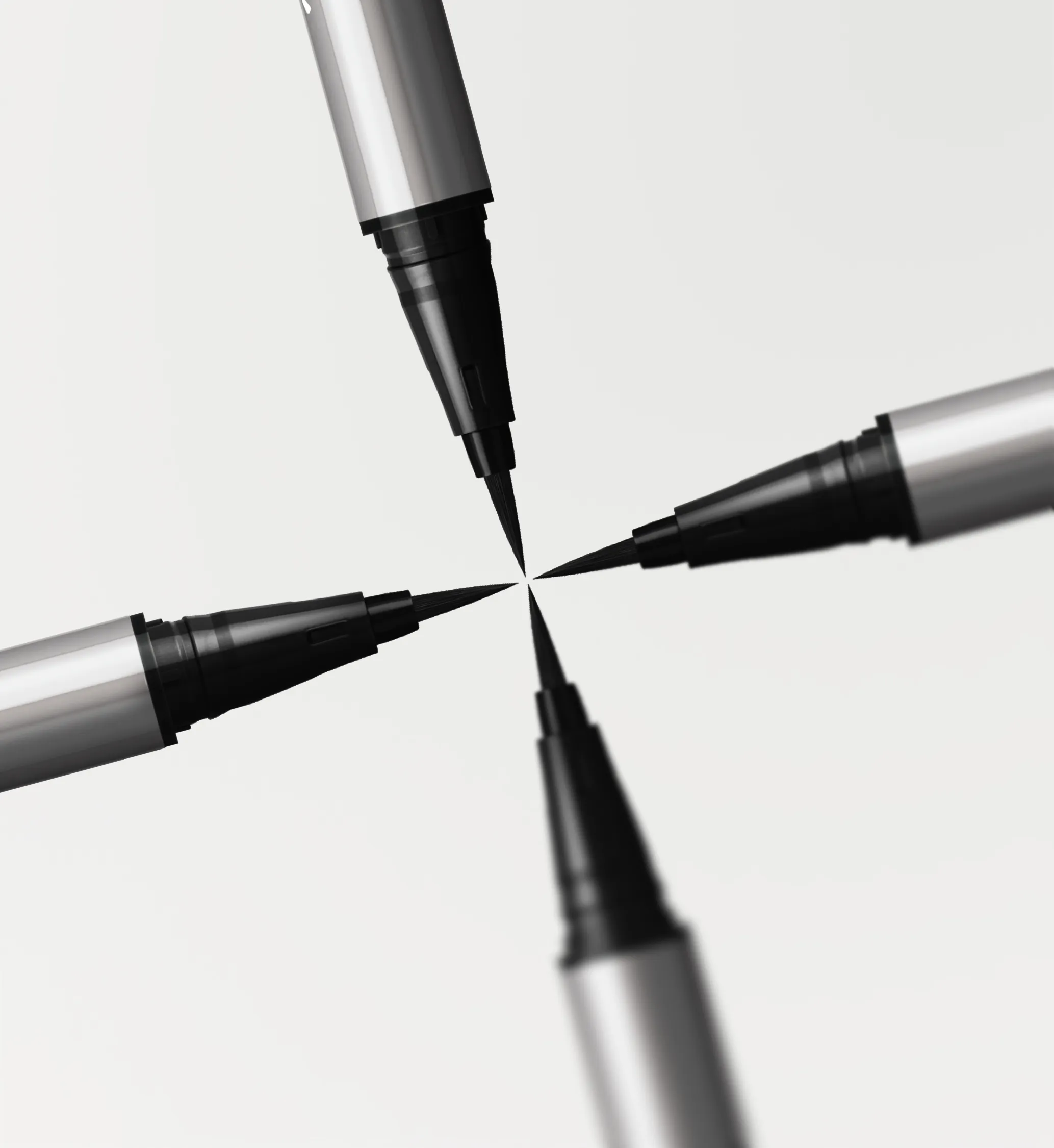 Four black brush love liner liquid markers with silver barrels arranged tip-to-tip in a cross on a light background.