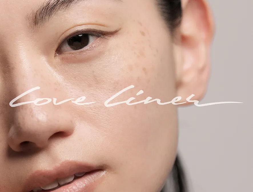 Close-up of a woman's freckled face with natural skin texture and lips slightly parted. Love liner logo on first plan