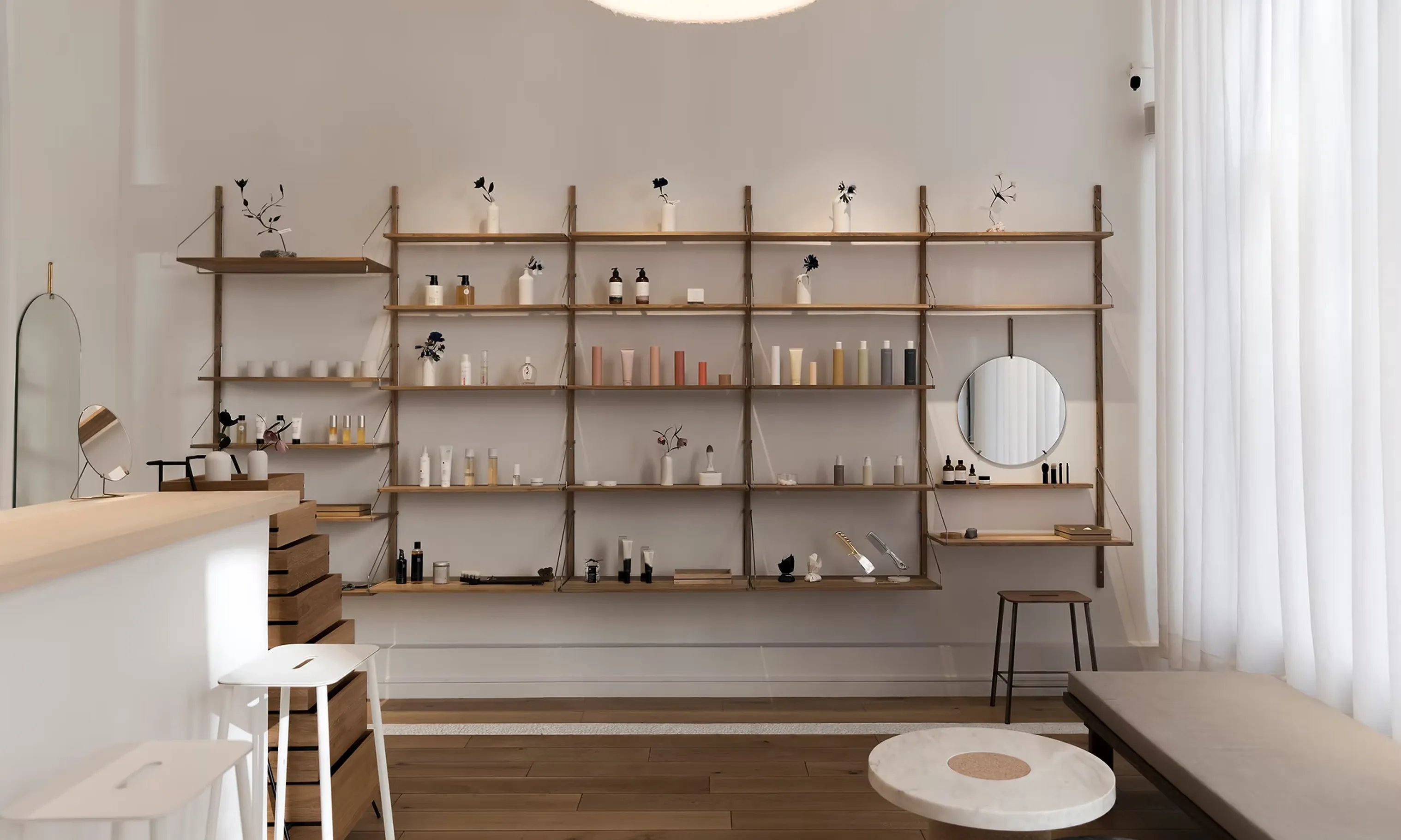 Minimalist bien; bijo beauty store interior with wooden shelves, cosmetic products, stools, and a round mirror.