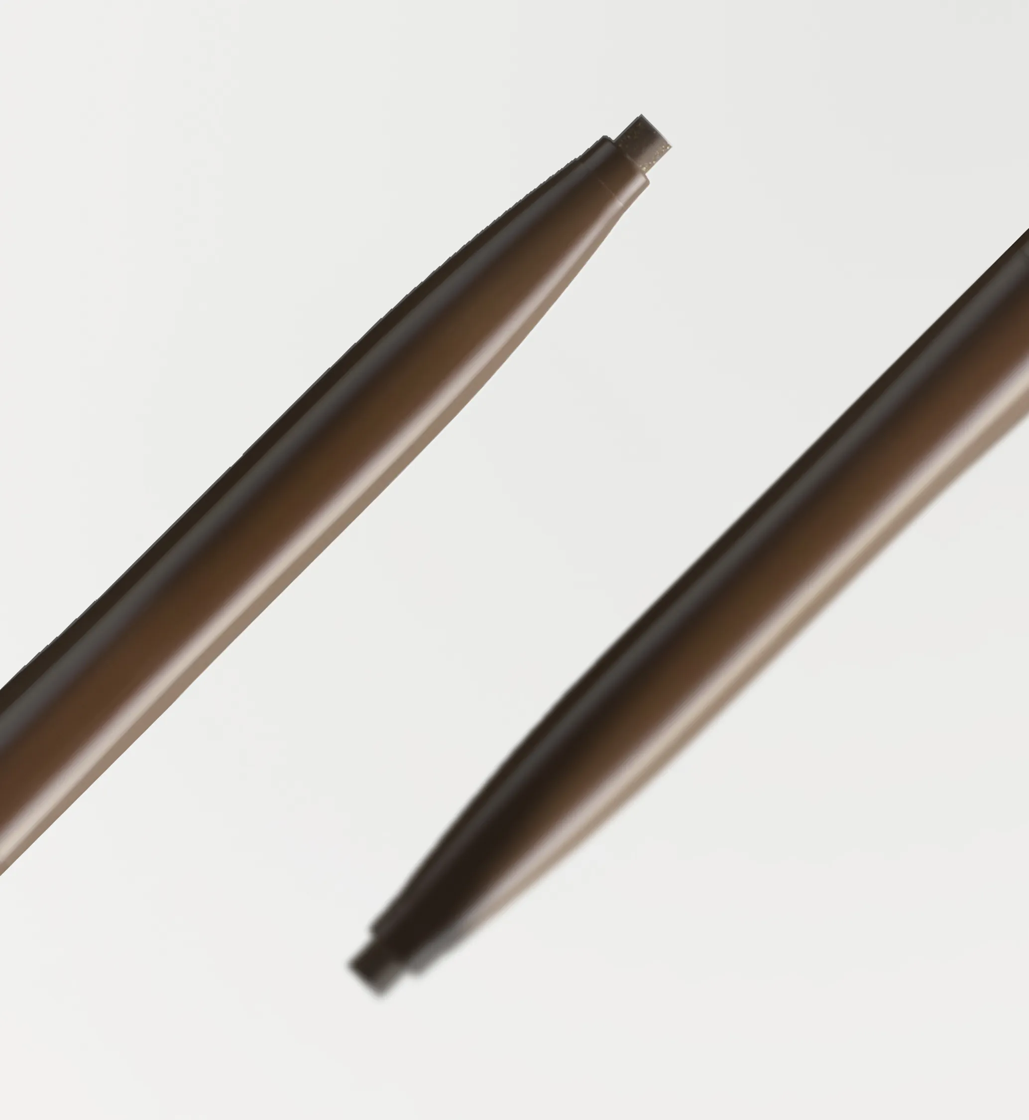 Two brown retractable eyeliner Love liner Creamfit pencils with slim barrels on a white background.