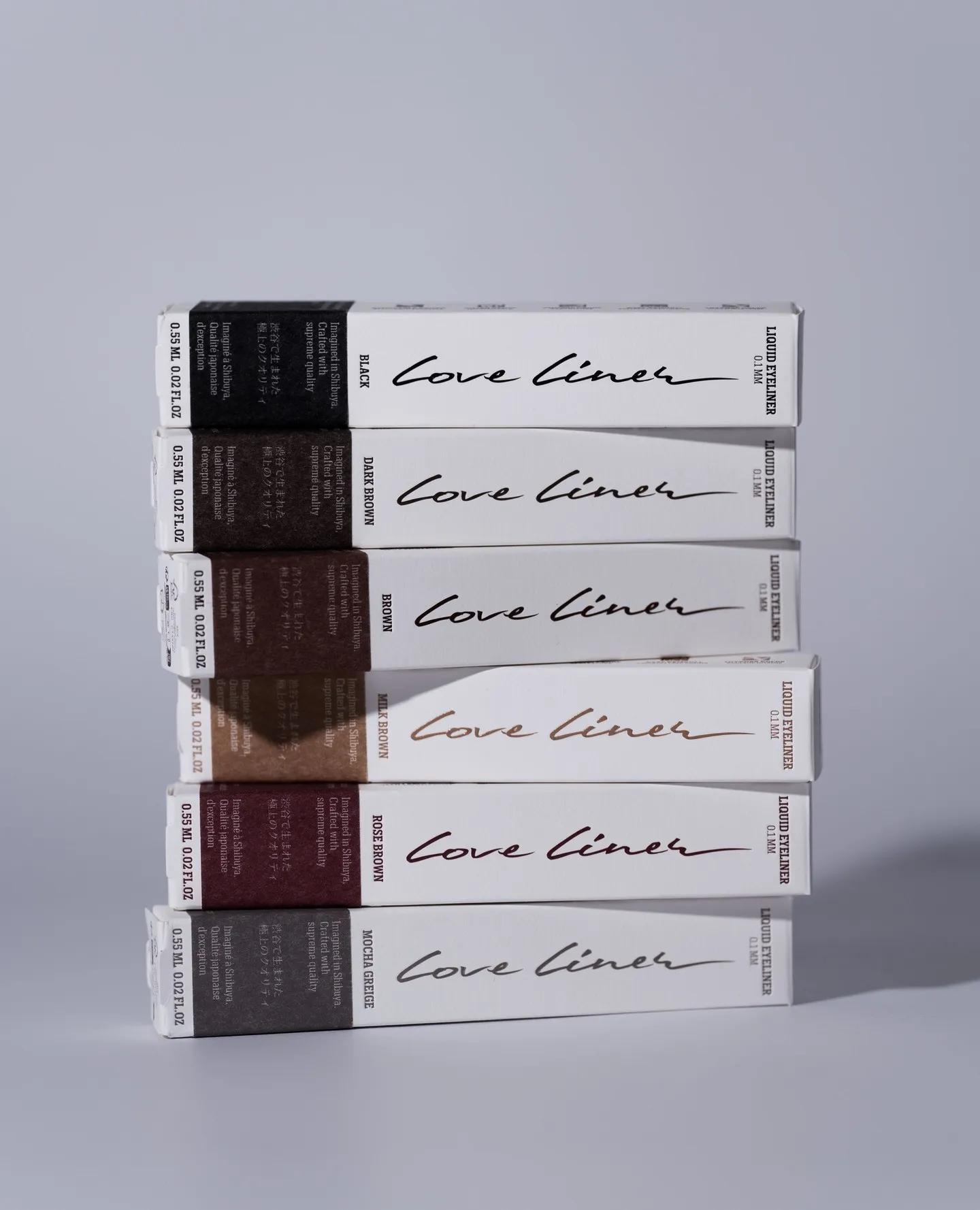 Six stacked boxes of Love Liner liquid eyeliners in black, dark brown, brown, milk brown, rose brown, mocha greige.