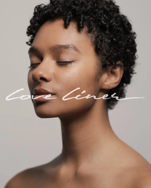 Young woman with short curly hair and closed eyes against a neutral background.