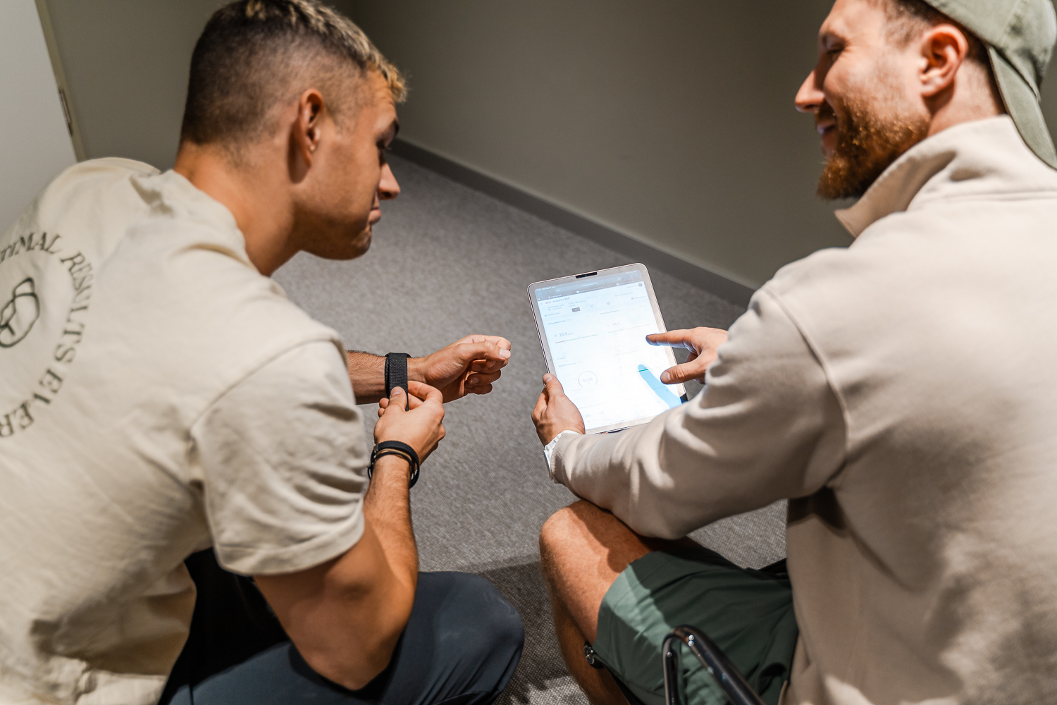Two men sitting and reviewing data on a tablet with one pointing at the screen.