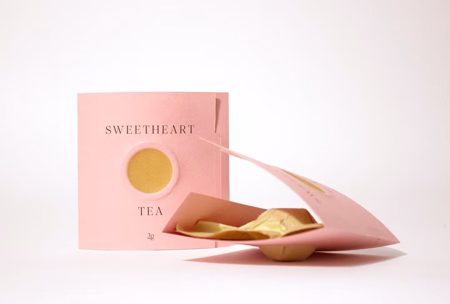 Tea packaging on white background, One laying down and slightly open.