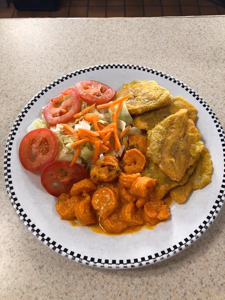 A plate of food with a variety of items including shrimp, carrots, and tomatoes.