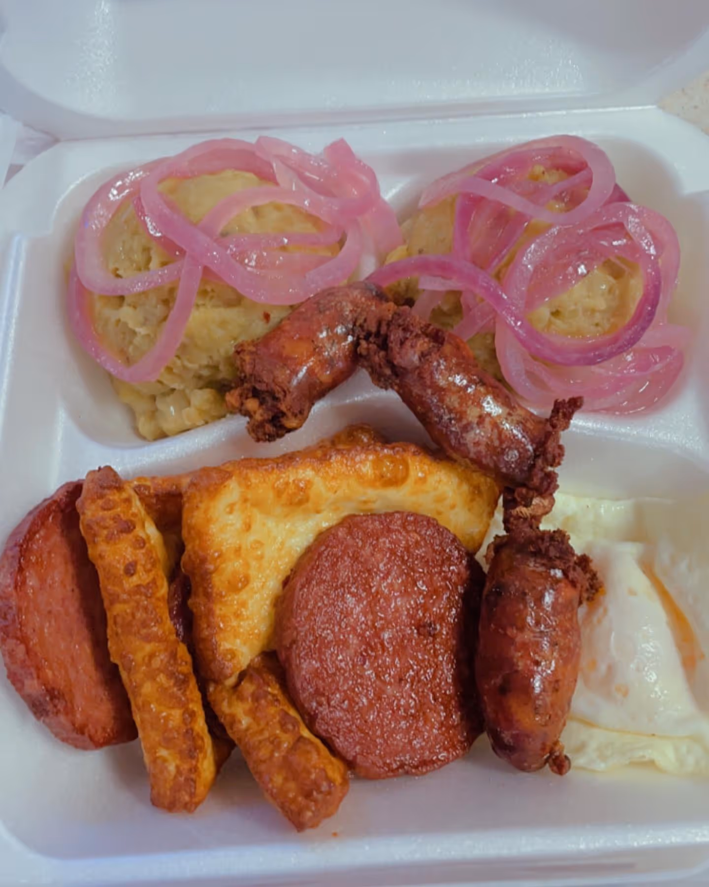 A white styrofoam container filled with various food items.