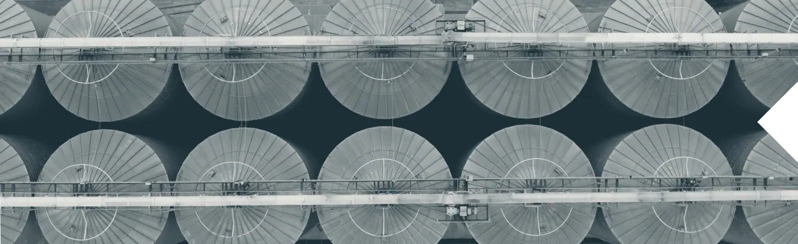 Aerial view of multiple large circular industrial storage silos arranged in two rows.