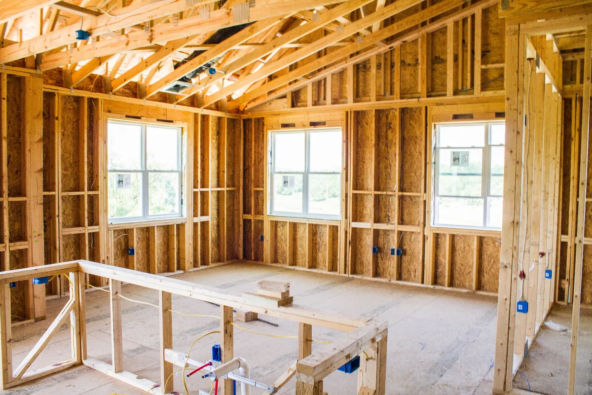 Partially constructed wooden room frame with visible windows, showing early stages of building.