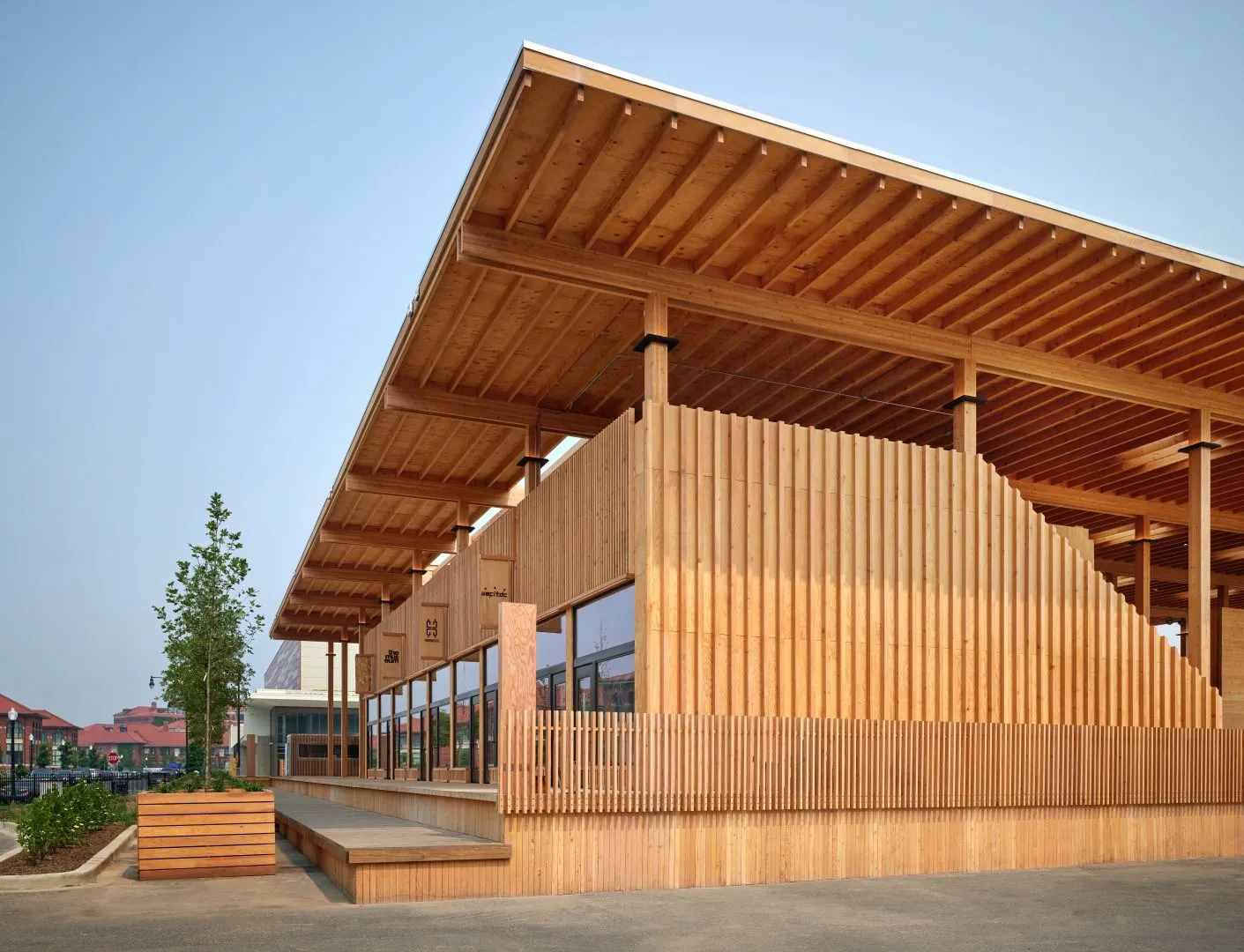 Modern wooden building with large overhanging roof and outdoor planter next to sidewalk.