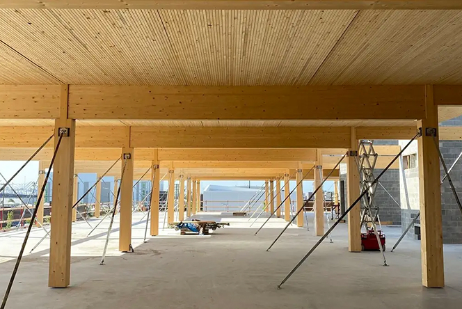 Wooden support beams and columns under construction in a large, open space with metal braces.