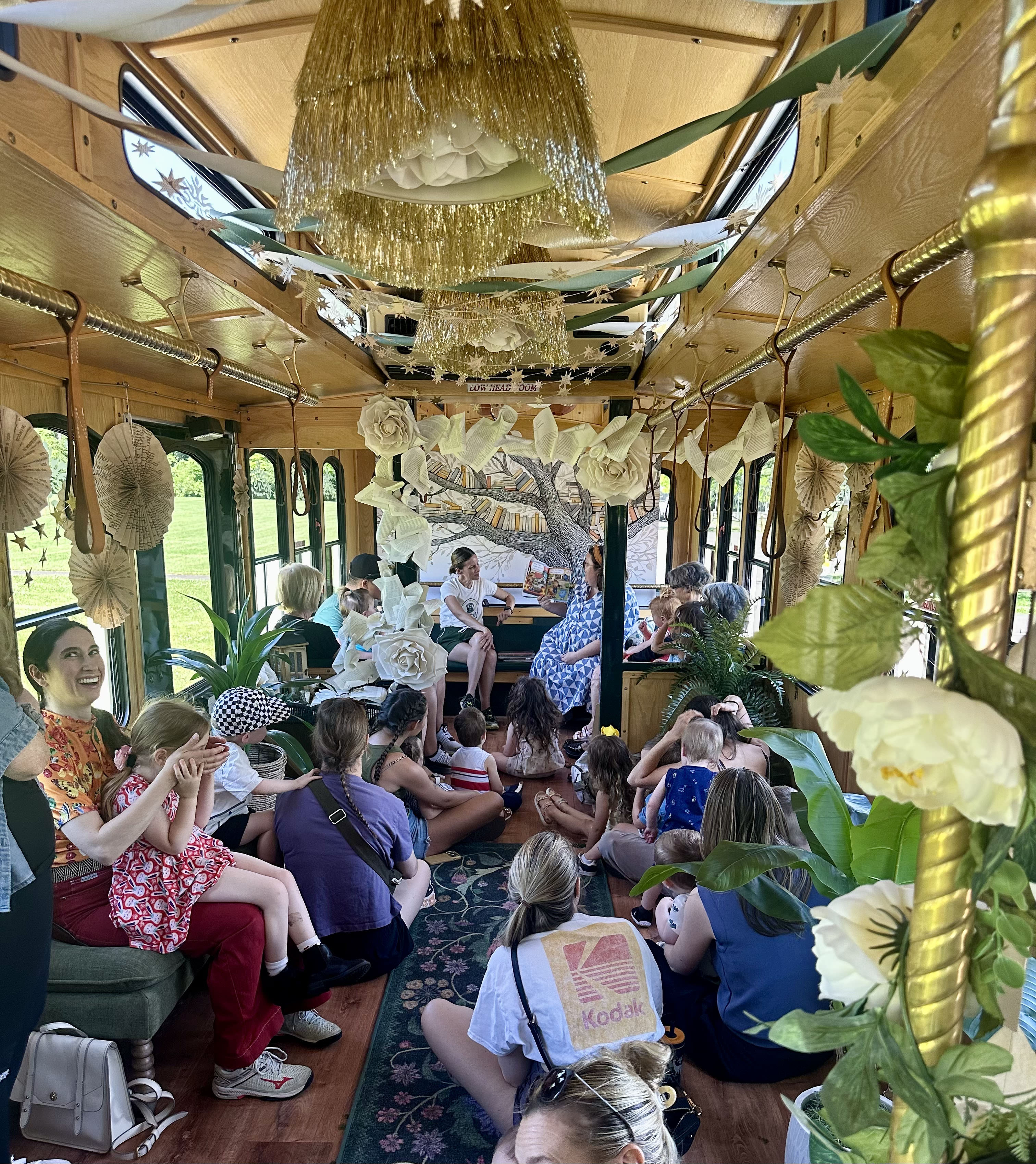 Children sit inside a trolley listening to someone read a book