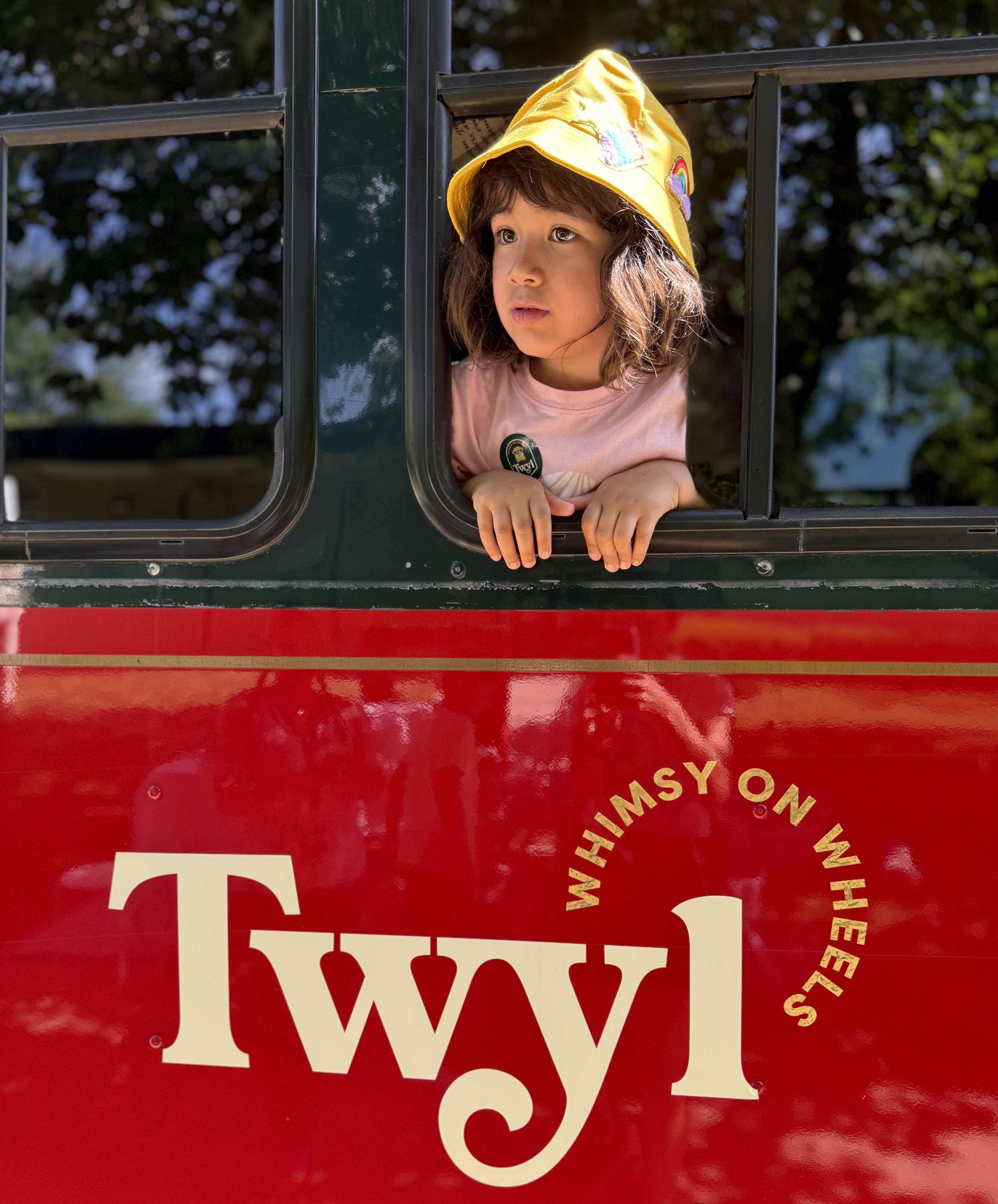 A small child leans out the window of a trolley