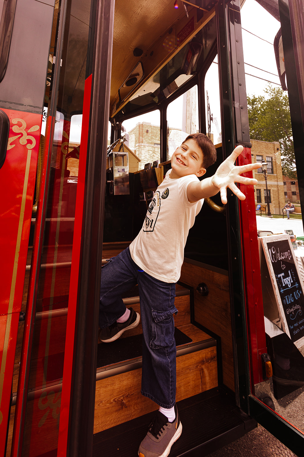 A boy waves in the doorway of a trolley