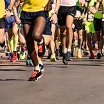 Runners' legs and feet moving on a paved road during a marathon or race.