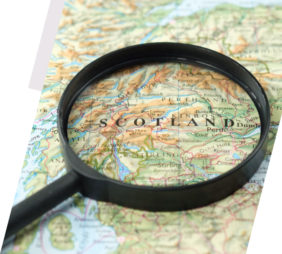 Magnifying glass focusing on the word Scotland on a detailed map showing nearby towns and features.