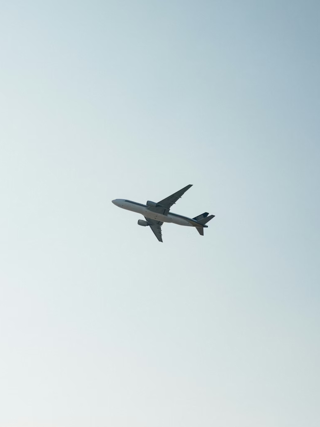 Commercial airplane flying in clear sky viewed from below.