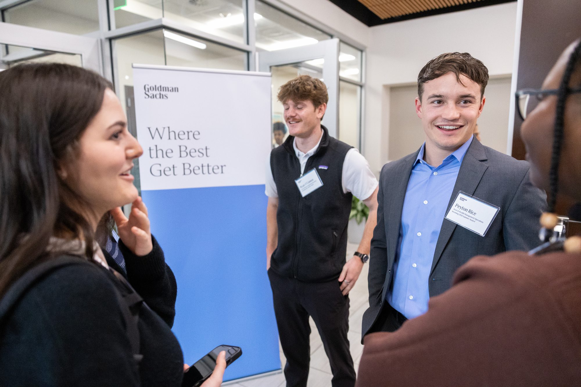 Attendees networking beside an event banner before a speaker session