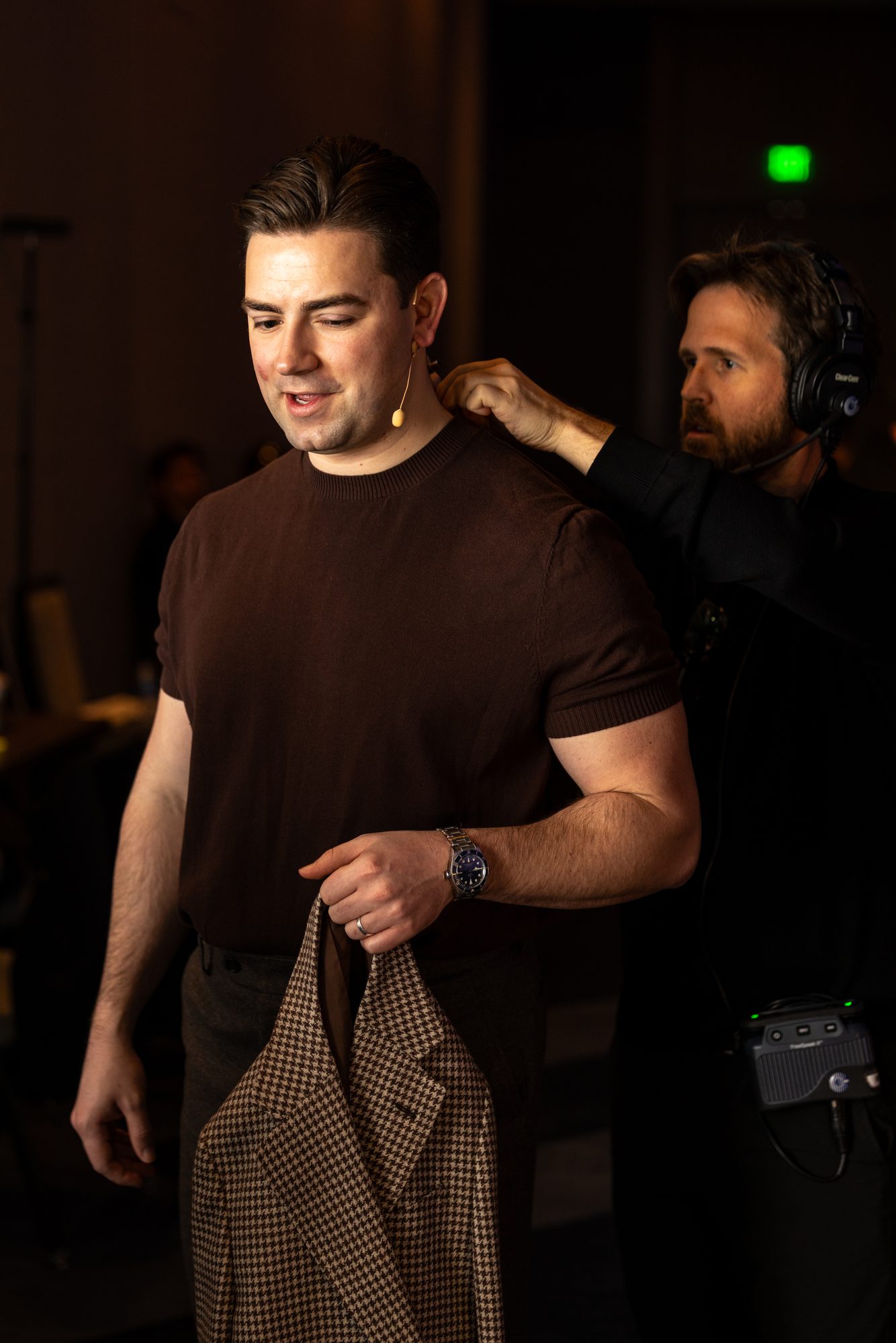 BW crew member fitting a lavalier microphone on a presenter backstage