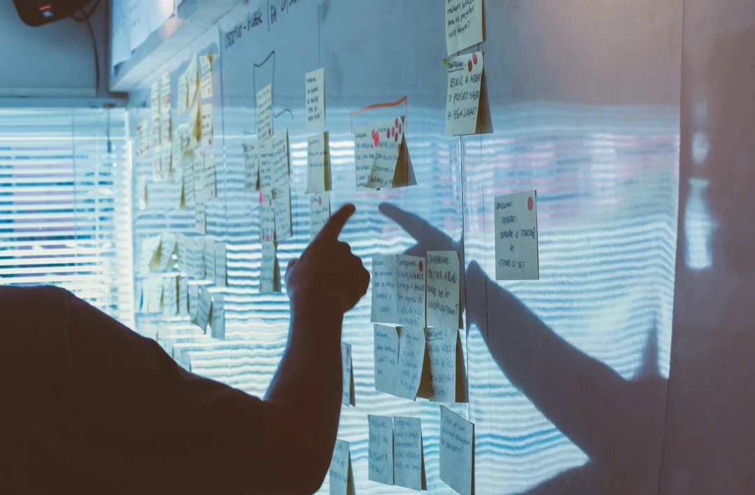 pointing to sticky notes on a whiteboard