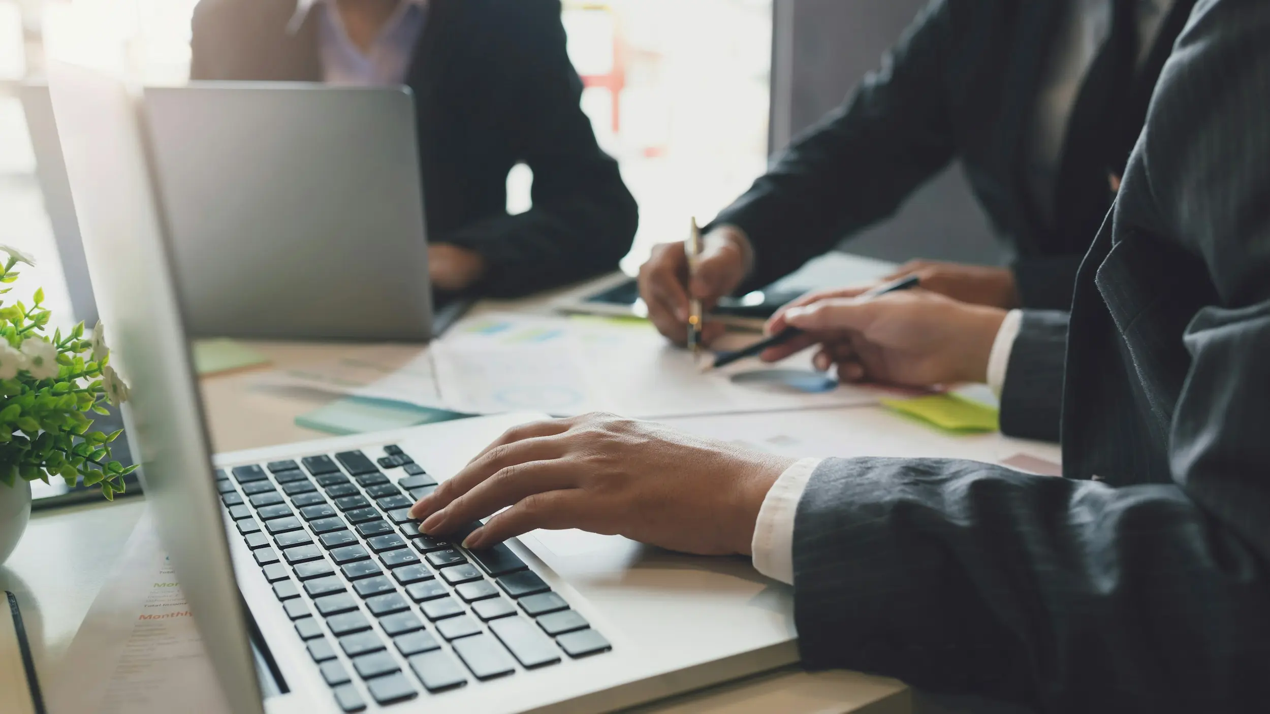 hand resting on keyboard while another takes notes on document
