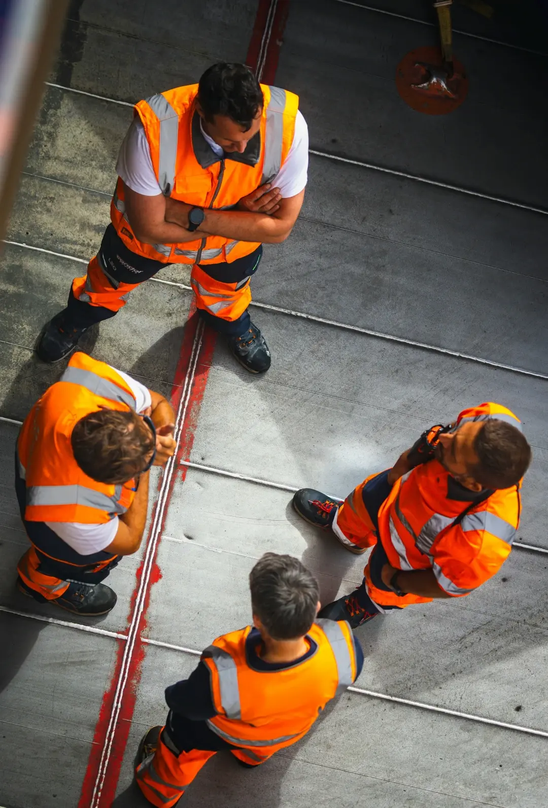 group of men standing around each other with orange safety vests
