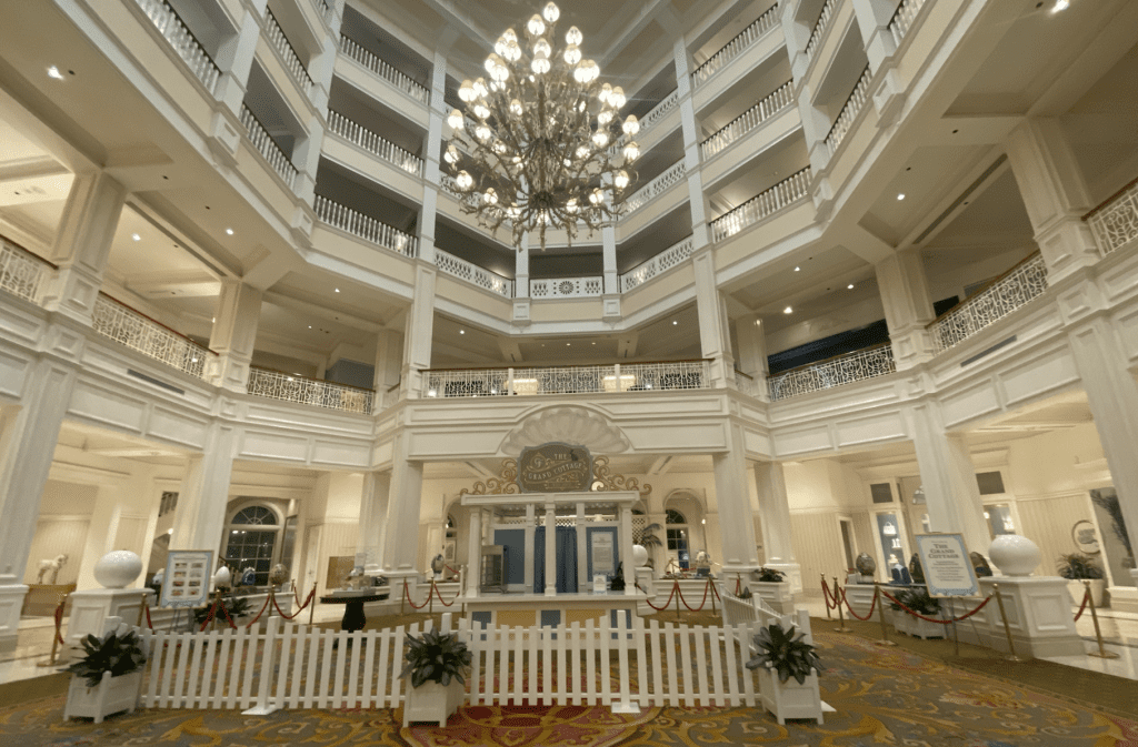 The Grand Cottage white, blue and yellow walk up treat kiosk in the Grand Floridian lobby. It's surrounded by a white picket fence.