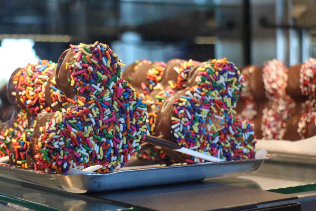 Mickey shaped chocolate treat on a stick covered in rainbow sprinkles