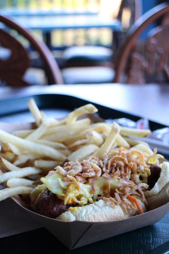 french fries and a sausage with slaw on a bun
