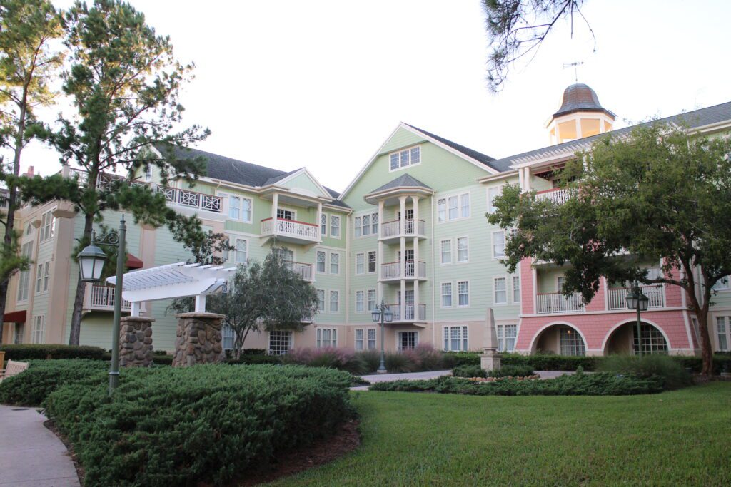 A spacious green lawn in front of a pink and green building multi story building