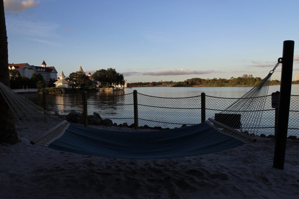 A sunset view of a hammock on a beach that overlooks where the fireworks go off at Magic Kingdom from the Polynesian with the castle in the distance.