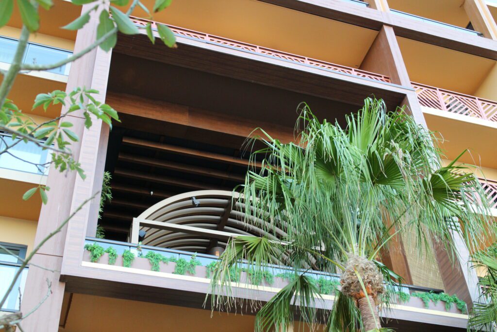 A palm tree stands in front of a cutout in the Polynesian Island Tower meant for firework viewing.