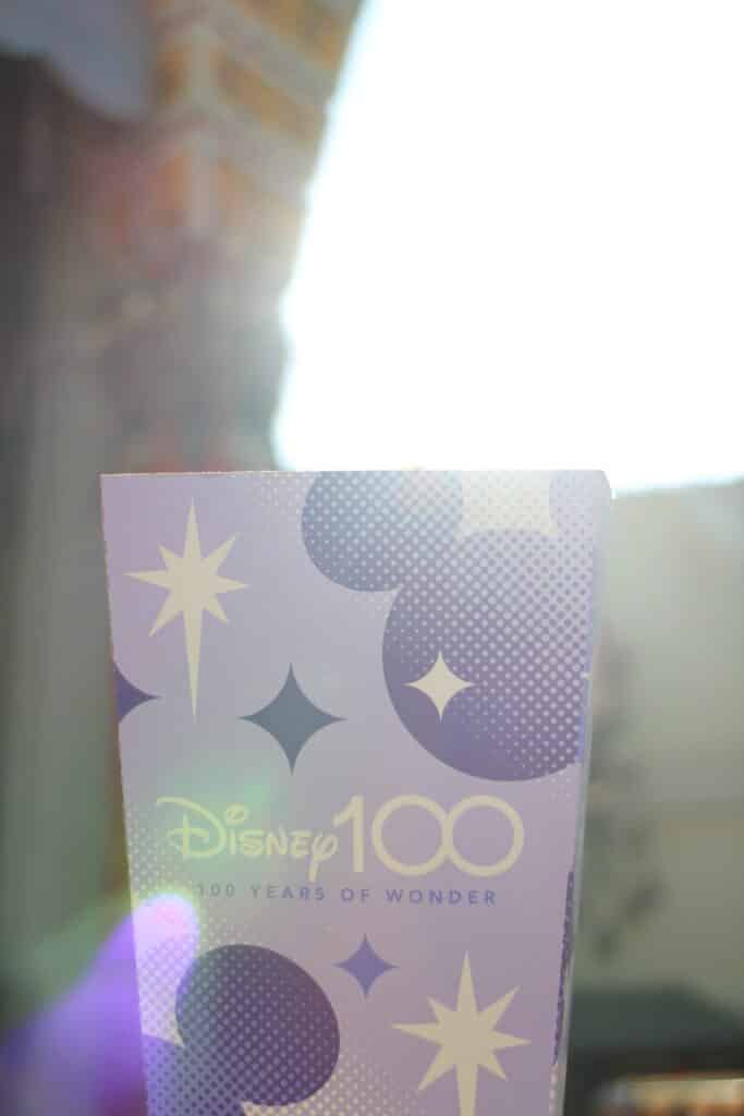 Disney 100 popcorn box that's lavender with dark purple Mickeys with a lens flair sparkling on it