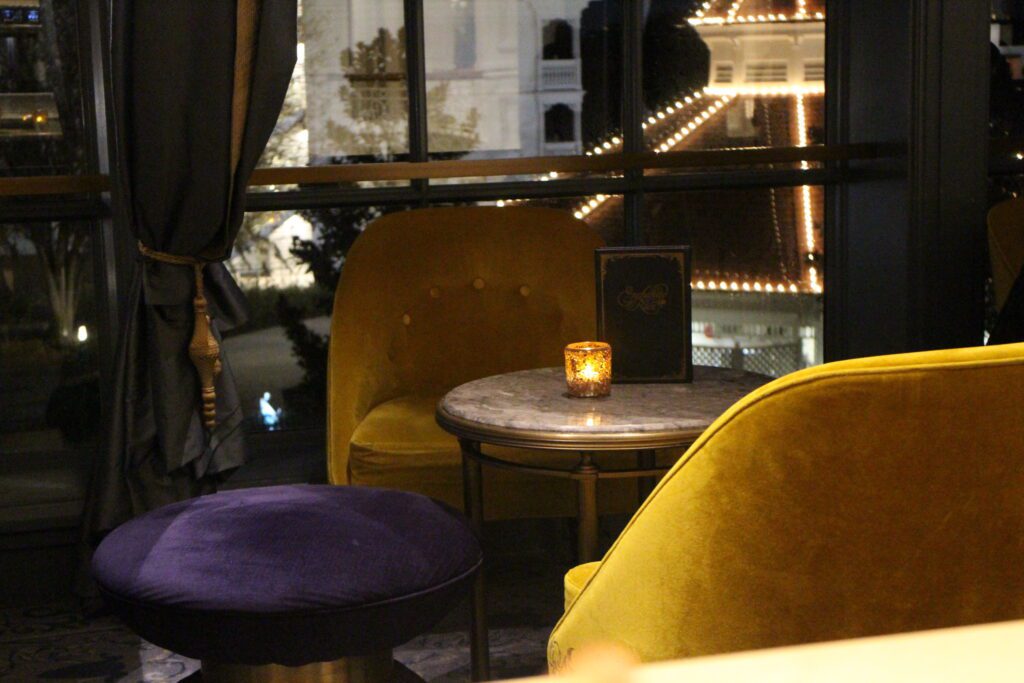 Modern, velvet seating in gem tones in front of a window at the Grand Floridian Enchanted Rose bar and lounge.