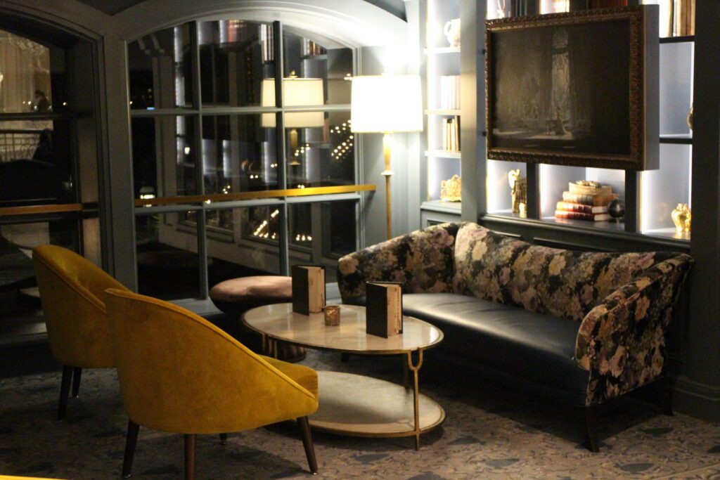 A dark corner of Enchanted Rose with lounge seating in front of a wall with shelves.