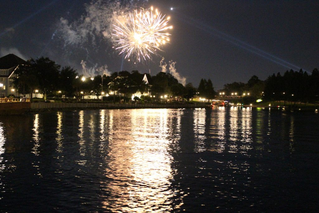 Disney fireworks reflect over water. These are free to enjoy with music from various resorts.