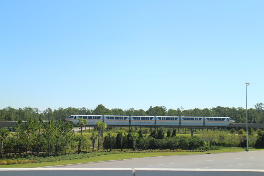 A monorail on its elevated track in front of a forest.