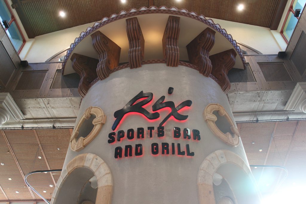 Rix Sports Bar and Grill in black writing with red lighting behind it on a themed circular pilar.