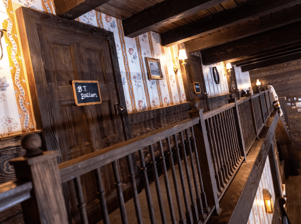 Inside McKim's Mile House Magic Kingdom DVC lounge, a rustic staircase on the second story.